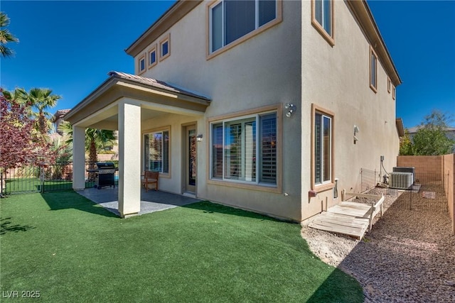 rear view of property with central AC, a fenced backyard, stucco siding, a yard, and a patio area