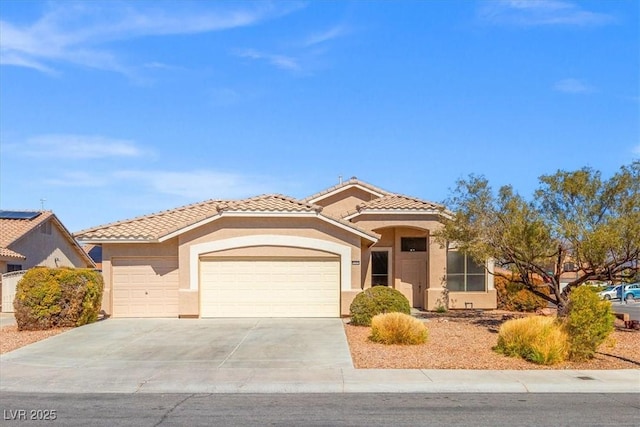 mediterranean / spanish home with a garage, concrete driveway, a tile roof, and stucco siding