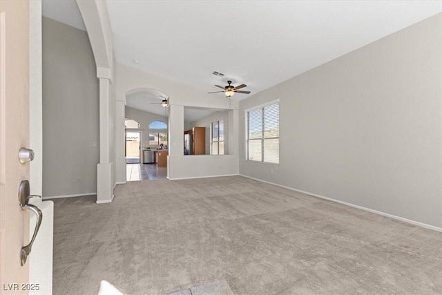 unfurnished living room with baseboards, visible vents, arched walkways, ceiling fan, and carpet floors