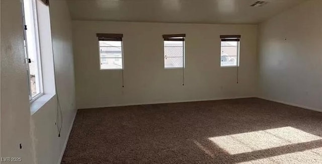 carpeted empty room featuring plenty of natural light and visible vents