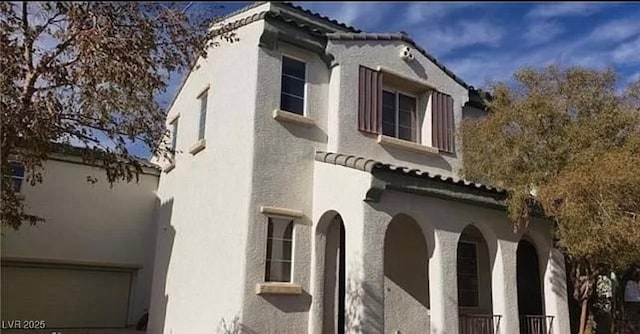 view of home's exterior with a garage, a tile roof, and stucco siding