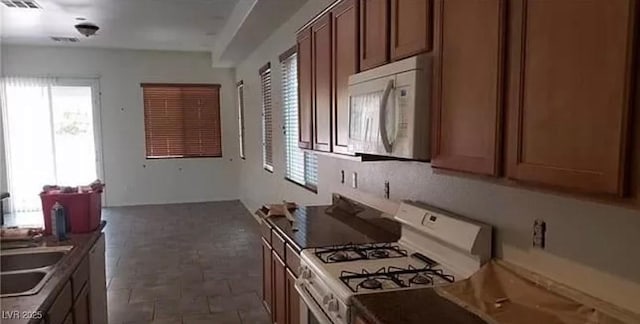 kitchen with white appliances, brown cabinets, a sink, and visible vents