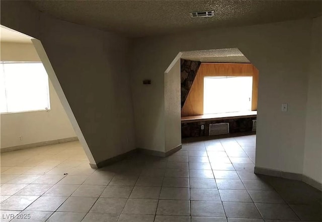 bonus room with light tile patterned floors, baseboards, visible vents, arched walkways, and a textured ceiling