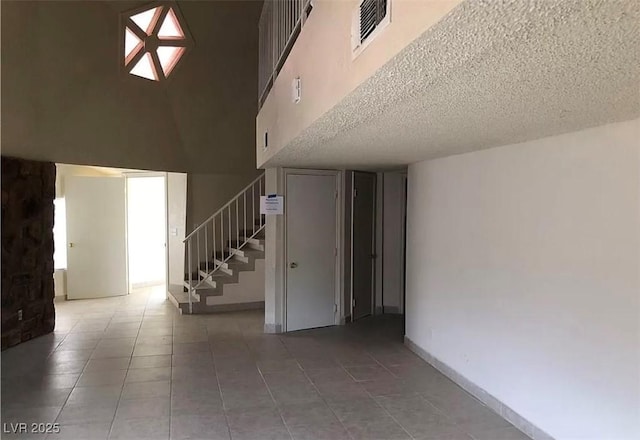 interior space with a towering ceiling, visible vents, stairway, and light tile patterned flooring