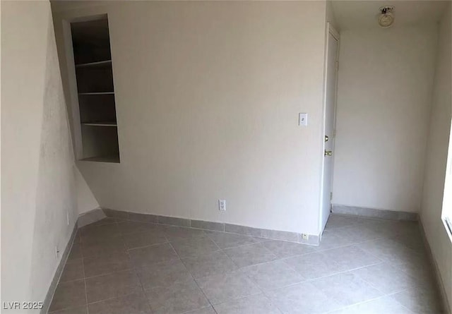 empty room featuring baseboards and tile patterned floors