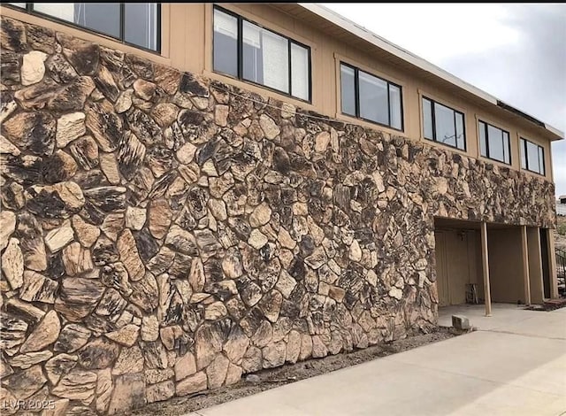 exterior space with stone siding and a patio