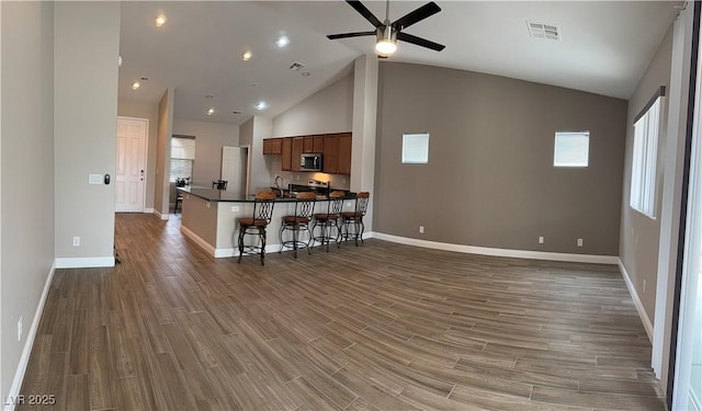 living area featuring ceiling fan, wood finished floors, visible vents, and baseboards