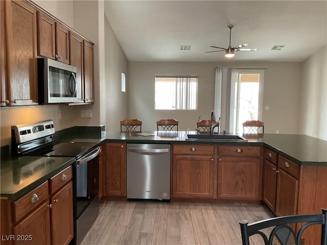 kitchen with stainless steel appliances, dark countertops, visible vents, and a sink