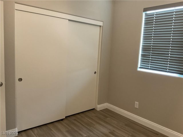 unfurnished bedroom with a closet, baseboards, and wood finished floors