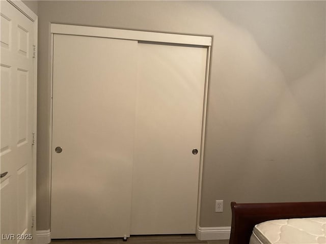 unfurnished bedroom with baseboards, a closet, and wood finished floors