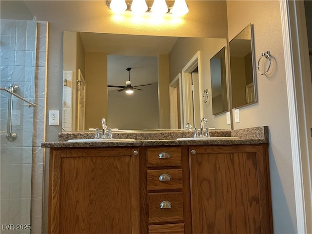 bathroom with ceiling fan, a sink, a tile shower, and double vanity