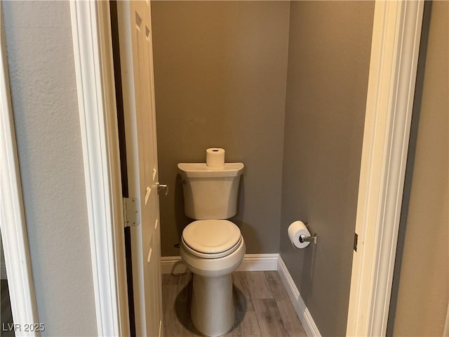 bathroom with wood finished floors, toilet, and baseboards