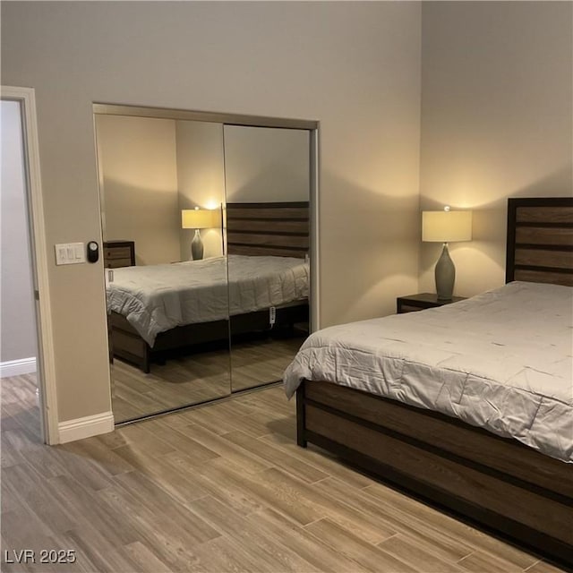 bedroom with a closet, wood finished floors, and baseboards