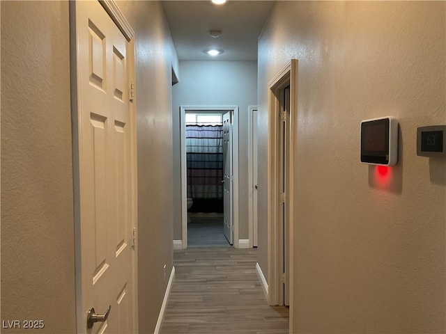 corridor with baseboards and wood finished floors