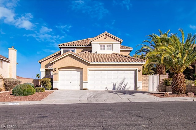 mediterranean / spanish house featuring driveway, a garage, fence, and stucco siding