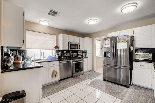 kitchen with appliances with stainless steel finishes, white cabinetry, visible vents, and a toaster