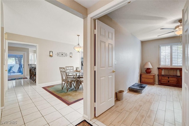 foyer featuring light tile patterned flooring, a ceiling fan, and baseboards