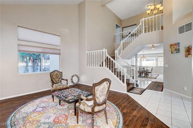 living area with a healthy amount of sunlight, high vaulted ceiling, visible vents, and a notable chandelier