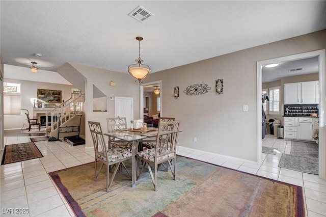 dining space featuring light tile patterned floors, ceiling fan, stairway, and visible vents