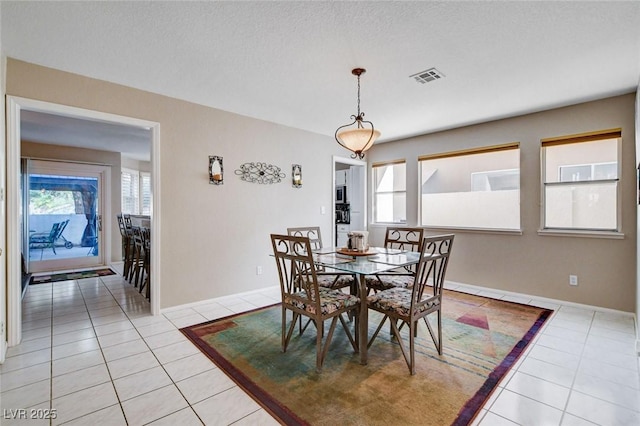 dining space with light tile patterned floors, baseboards, visible vents, and a textured ceiling