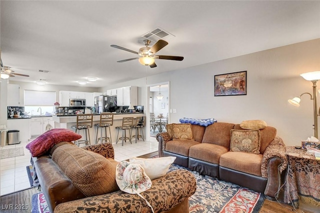 living room featuring light tile patterned floors, visible vents, and a ceiling fan