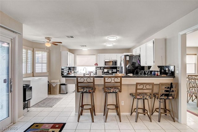 kitchen with a peninsula, dark countertops, visible vents, and stainless steel appliances