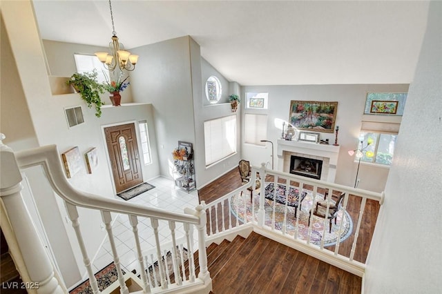 foyer entrance featuring plenty of natural light, a fireplace, an inviting chandelier, and wood finished floors