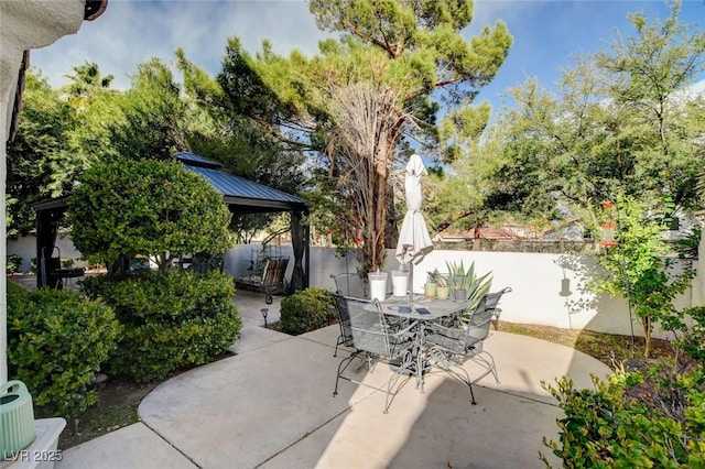 view of patio with a gazebo, outdoor dining area, and fence