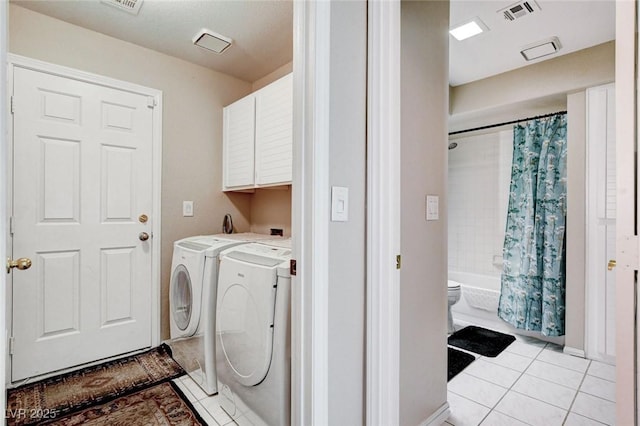 laundry area featuring visible vents, light tile patterned floors, washing machine and dryer, and cabinet space