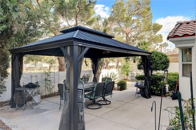 view of patio featuring outdoor dining area, fence, and a gazebo