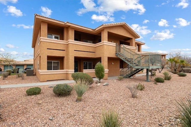 exterior space with a balcony, stairway, and stucco siding