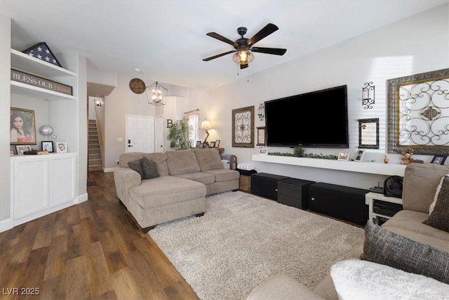 living room featuring ceiling fan with notable chandelier, stairway, and wood finished floors