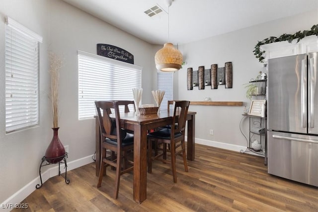 dining area with baseboards, visible vents, and wood finished floors