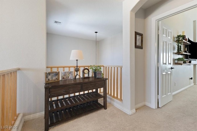 hallway featuring carpet, visible vents, and baseboards