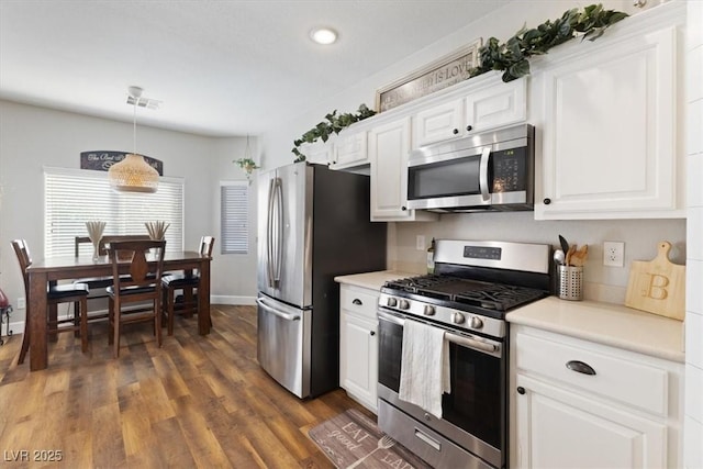 kitchen with stainless steel appliances, light countertops, visible vents, and dark wood finished floors