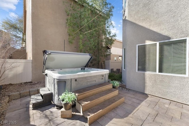 view of patio / terrace featuring fence and a hot tub