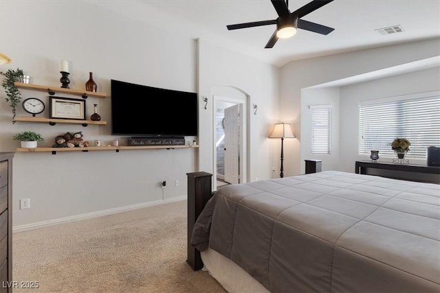 carpeted bedroom with baseboards, visible vents, vaulted ceiling, and a ceiling fan