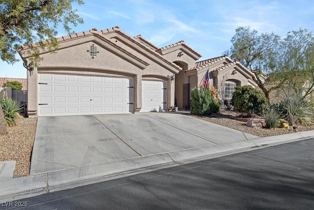 mediterranean / spanish-style house featuring stucco siding, concrete driveway, fence, a garage, and a tiled roof