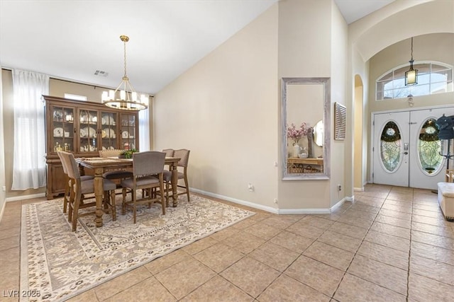 tiled dining space with arched walkways, high vaulted ceiling, visible vents, baseboards, and an inviting chandelier