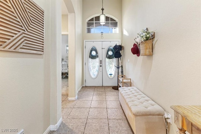 entrance foyer featuring arched walkways, a healthy amount of sunlight, a high ceiling, and light tile patterned floors