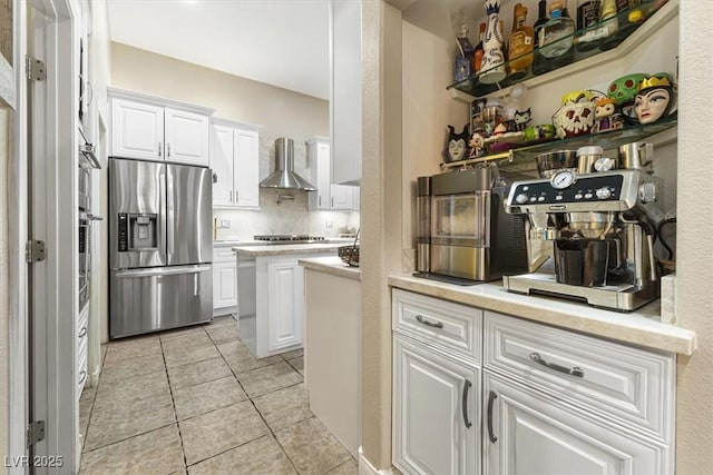 kitchen featuring light tile patterned floors, white cabinets, wall chimney exhaust hood, stainless steel appliances, and light countertops