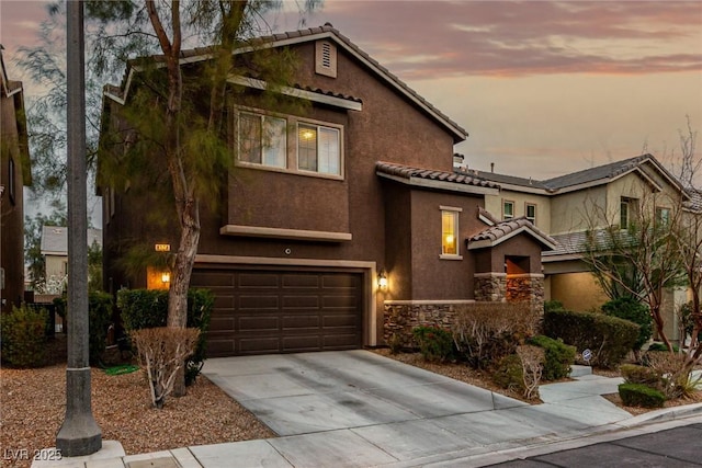 view of front facade with an attached garage, driveway, stone siding, a tiled roof, and stucco siding