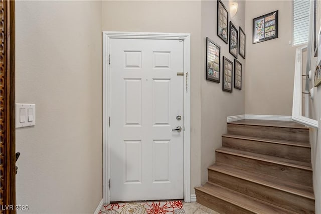 doorway to outside featuring light tile patterned floors, baseboards, and stairs