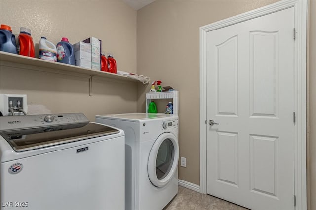 washroom featuring light tile patterned floors, laundry area, washer and clothes dryer, and baseboards