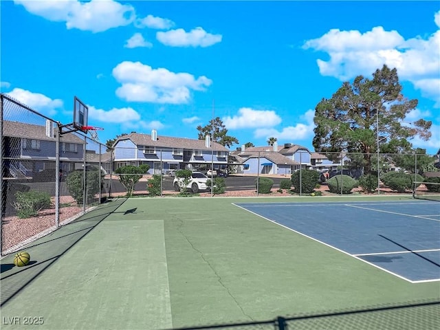 view of tennis court with community basketball court, a residential view, and fence