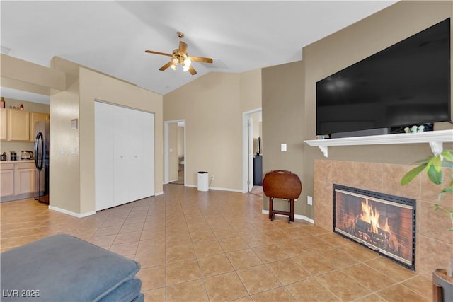 living room with vaulted ceiling, light tile patterned flooring, a tile fireplace, and baseboards