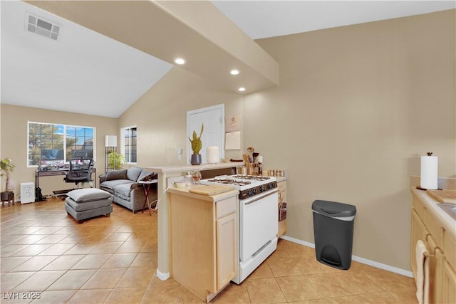 kitchen with white range with gas stovetop, visible vents, vaulted ceiling, light countertops, and light tile patterned flooring