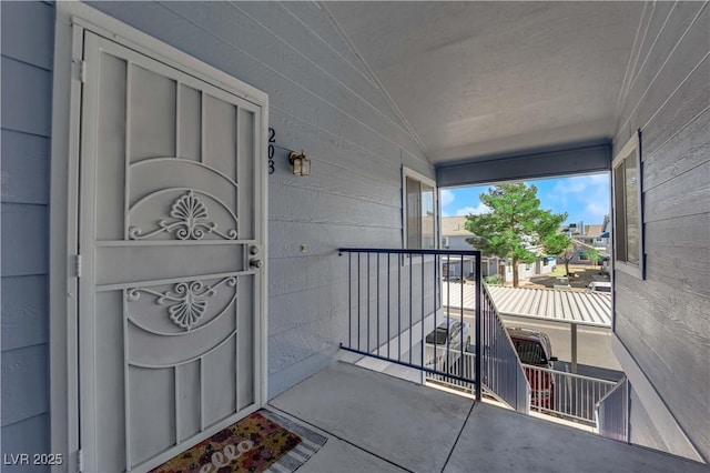 view of exterior entry featuring concrete block siding and a balcony