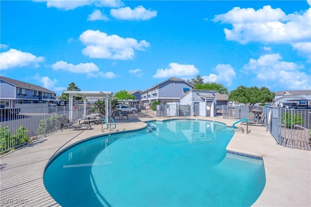 view of swimming pool featuring a residential view, fence, a fenced in pool, and a patio