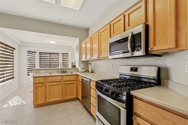 kitchen with light tile patterned floors, a sink, light countertops, appliances with stainless steel finishes, and light brown cabinetry